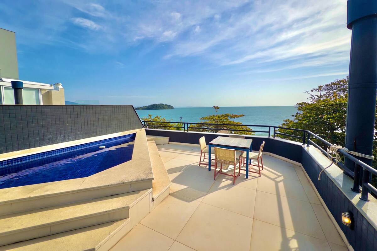 A rooftop terrace with a swimming pool, outdoor seating, and a view of the sea.