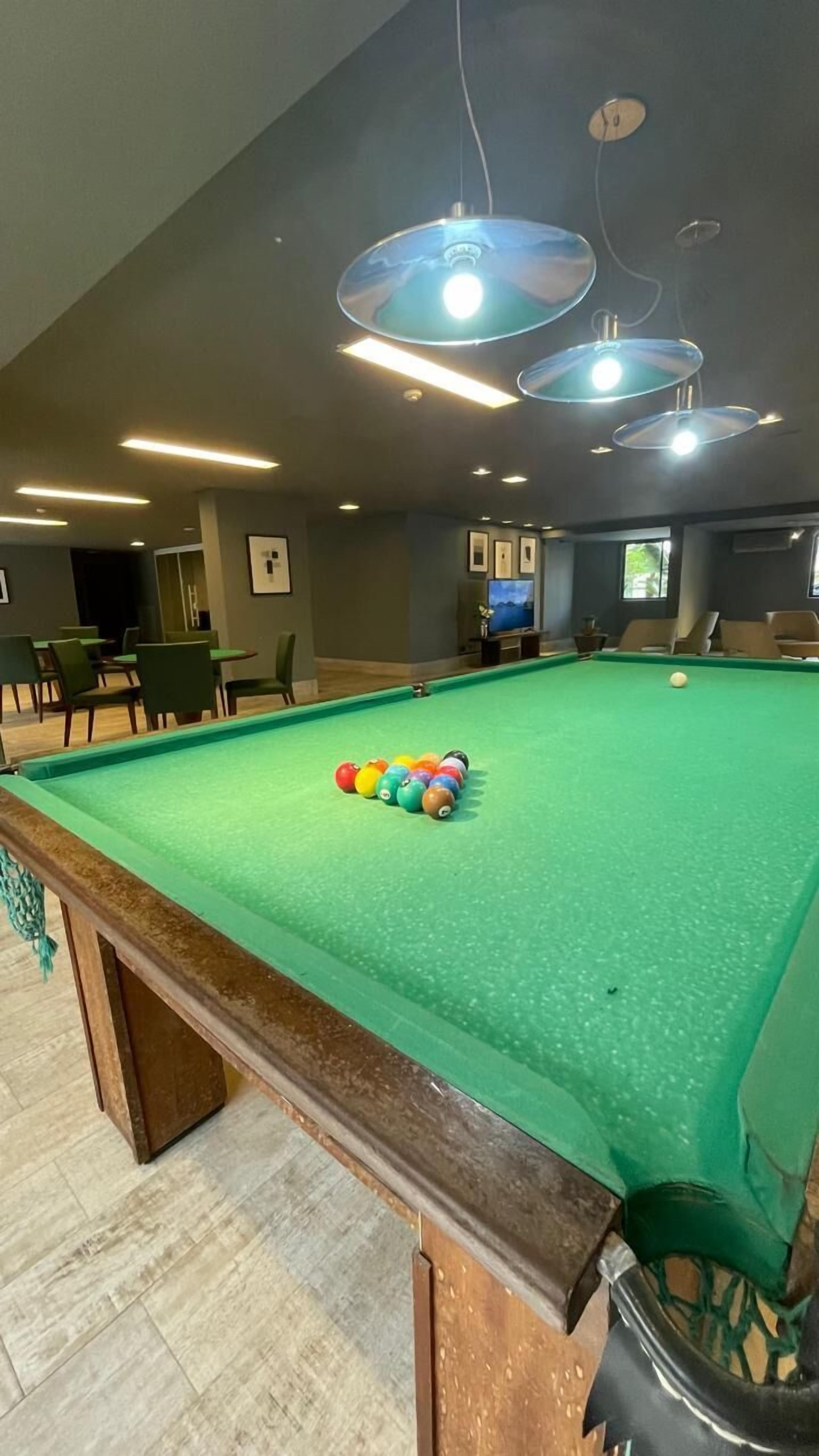A pool table with balls, overhead lighting, and a billiard cue.