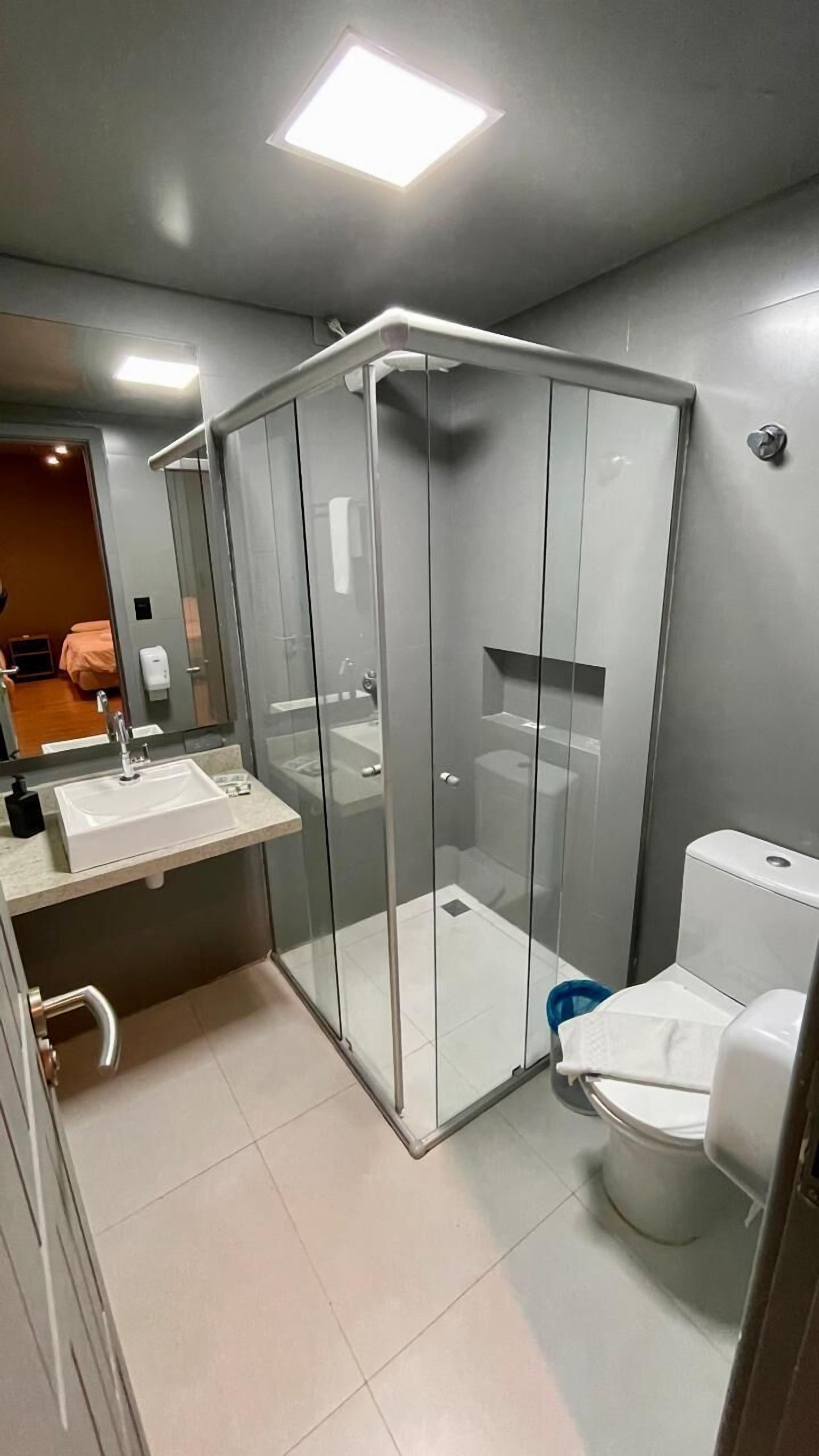 Un baño moderno con ducha de vidrio, lavamanos e inodoro.