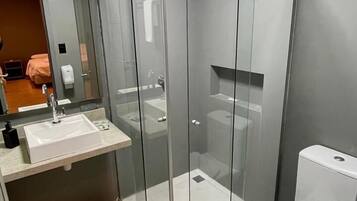 Un baño moderno con ducha de vidrio, lavamanos e inodoro.