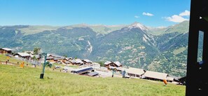 Un pueblo de montaña con casas de madera tradicionales, un telesilla y vistas de las montañas circundantes.