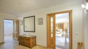 A hallway with a wooden cabinet, a large mirror, and a door leading to a living area. - Quinta do Sol in Guia (Albufeira)