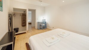 A hotel room with a bed, a desk, a chair, and a wardrobe.