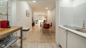 A modern kitchen with a sink, dining area, and a hallway leading to a living space.