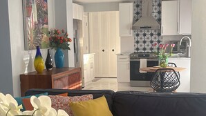 A modern living room with a dark sofa, a coffee table with a remote control, and a vase with flowers. - Enjoy SWFL (Fort Myers)