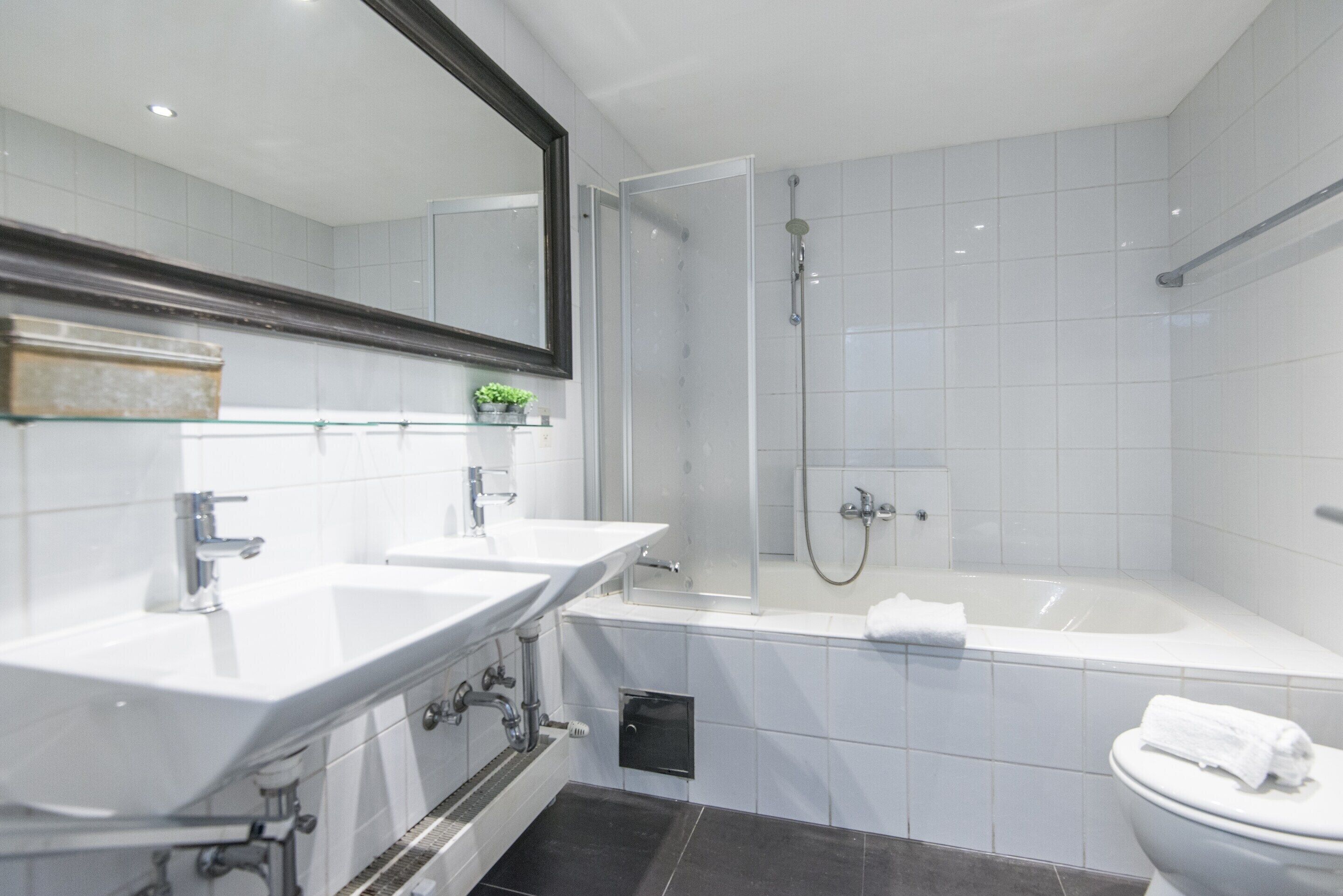 Une salle de bain moderne avec deux lavabos, une baignoire et une douche.