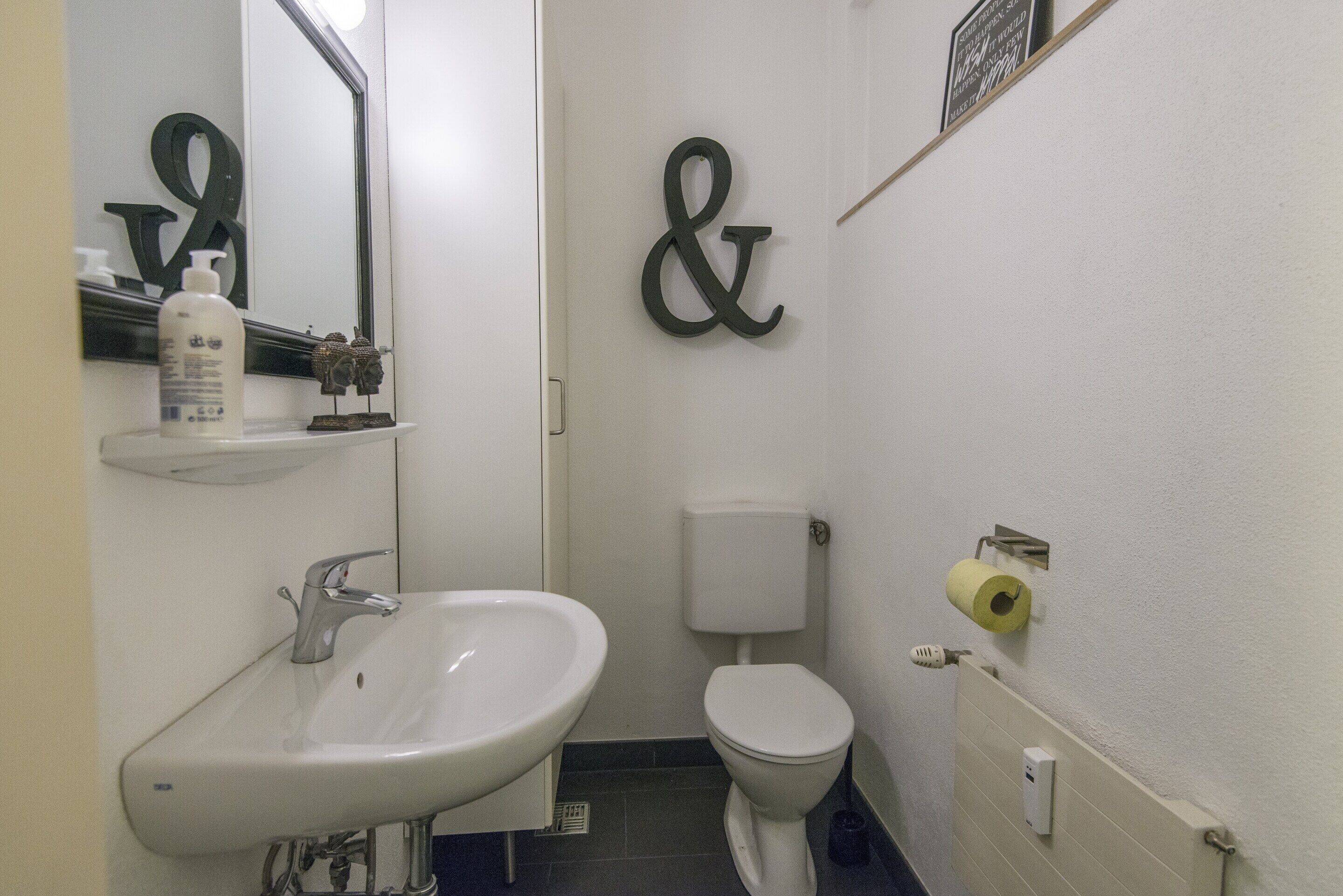 Un baño con lavamanos, inodoro y espejo.
