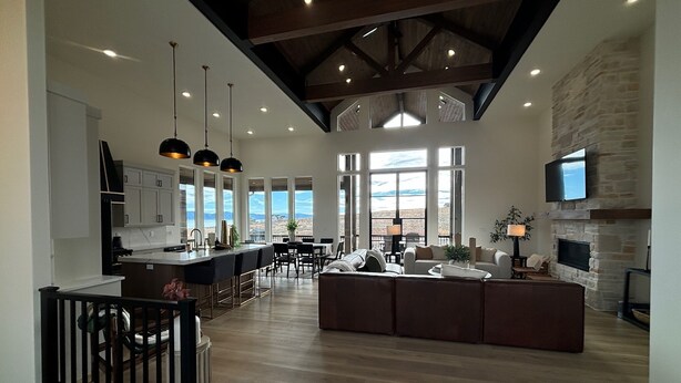 A spacious living area with a large island, a kitchen with high ceilings, and a stone fireplace.