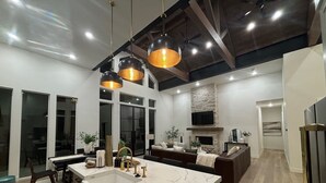 A spacious kitchen with a large island, a stone fireplace, and modern pendant lighting.