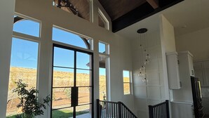 A spacious interior with large windows, a wooden ceiling, and a view of a desert landscape.