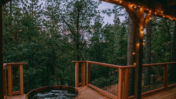 Een houten terras met een jacuzzi en een houten leuning.