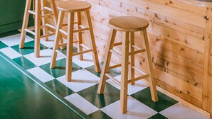 Een keuken met een houten bar, drie krukken en bloemenbehang.
