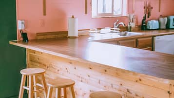 Una cocina con barra de madera, tres taburetes y papel tapiz con estampado floral.