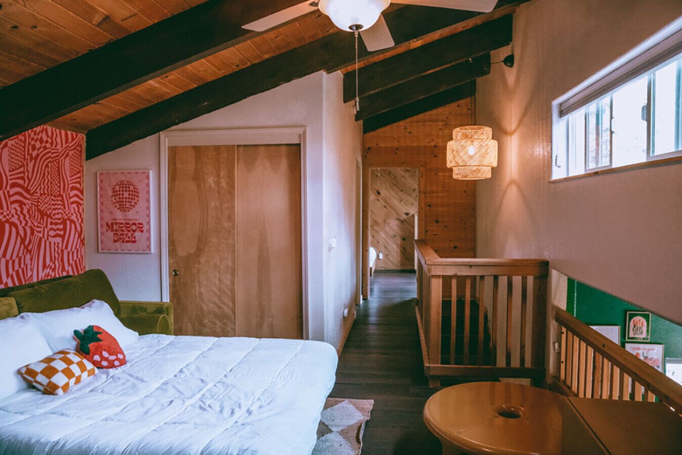 Un dormitorio acogedor con cama, techo de madera, una escalera y vistas al exterior.