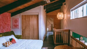 Een gezellig slaapkamer met een bed, een houten plafond, een trap en uitzicht op buiten.