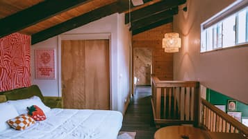 Un dormitorio acogedor con cama, techo de madera, una escalera y vistas al exterior.