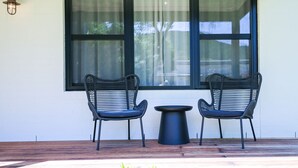 Two wicker chairs and a small round table on a wooden deck, with a large window in the background. - Manning Retreat - your family haven on Gavan St (Bright)