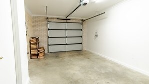 Un garage avec une porte fermée, une pile de bois de chauffage et un sol en béton.