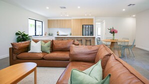 A modern living room with a leather sofa, a wooden coffee table, and a dining area with a table and chairs. - Manning Retreat - your family haven on Gavan St (Bright)