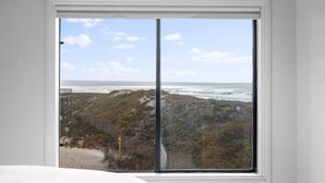 Una habitación con un gran ventanal con vista a la playa y al océano.