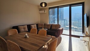 Un espacio moderno con comedor, sofá y un amplio ventanal con vista a la ciudad.