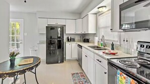 Een moderne keuken met witte kasten, roestvrijstalen apparatuur en een eethoek met een ronde tafel en stoelen.