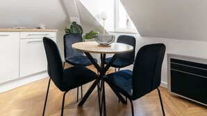 Een moderne eetruimte met een ronde tafel, vier zwarte stoelen en een centraal hanglamp.