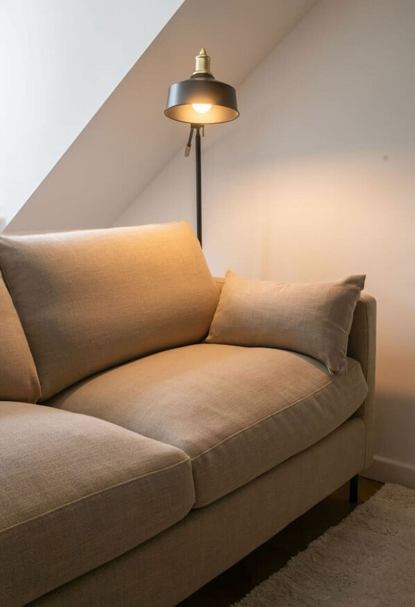 A beige sofa in a corner with a black floor lamp.