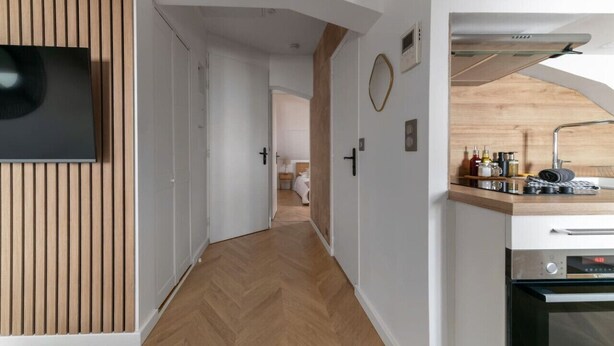 Een moderne keuken met een ingebouwde oven, een houten aanrechtblad en een visgraatvloer.
