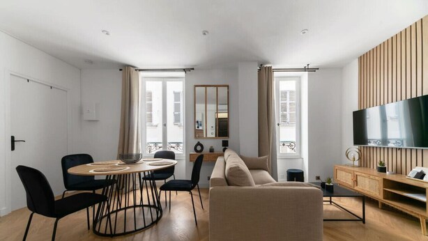 Un salon moderne comprenant un canapé, une table à manger, des chaises et un téléviseur.