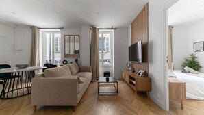 Un salon moderne comprenant un canapé, une table basse, un téléviseur et un coin repas avec une table et des chaises.
