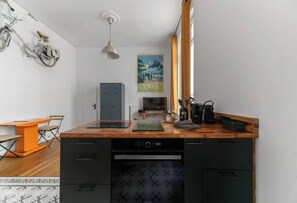 A compact kitchen with a wooden countertop, a dishwasher, and a small dining area with a table and chairs.