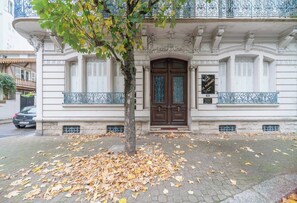 A building with a large wooden door, white walls, and decorative iron railings.