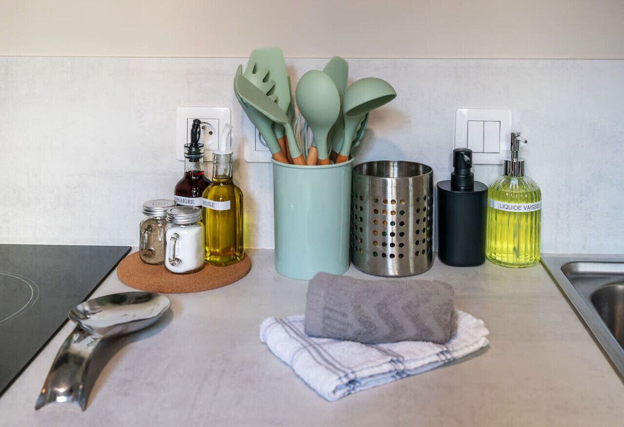 Una encimera de cocina con varios utensilios, botellas y un paño.