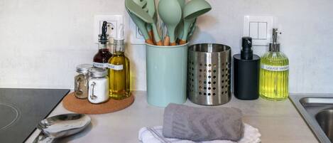 Una encimera de cocina con varios utensilios, botellas y un paño.