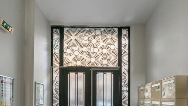A hallway with a patterned door, a bulletin board, and a row of storage cabinets.