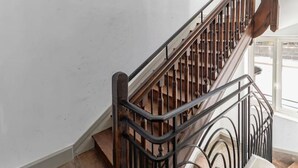 A wooden staircase with a black metal railing in a room with wooden flooring and white walls.