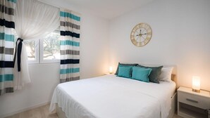 A bedroom with a bed, a nightstand, a wall clock, and curtains. - Beautiful Apartment With Parking Space (Porec)