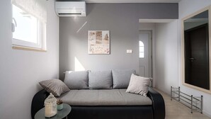 A modern living room with a grey sofa, a small round table with a decorative item, and a large window. - Beautiful Apartment With Parking Space (Porec)