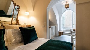 Un dormitorio con cama, almohadas, un espejo y vista a un baño por un arco.