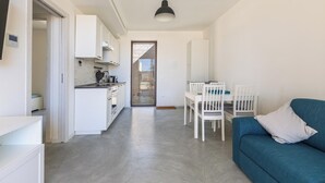 Une cuisine moderne avec des meubles blancs et un coin repas comprenant un canapé bleu et des chaises blanches.