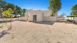 Un bâtiment moderne avec une allée en gravier, une entrée avec une porte en verre et un petit espace patio.