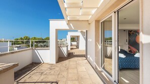 Een modern balkon met helder uitzicht over de stad, een schuifglazen deur die naar een slaapkamer leidt, en een betegelde vloer.