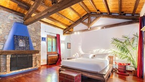 A bedroom with a wooden ceiling, a fireplace, a bed, and a large window. - Cascina Monferrato 12, Emma Villas (Sala Monferrato)