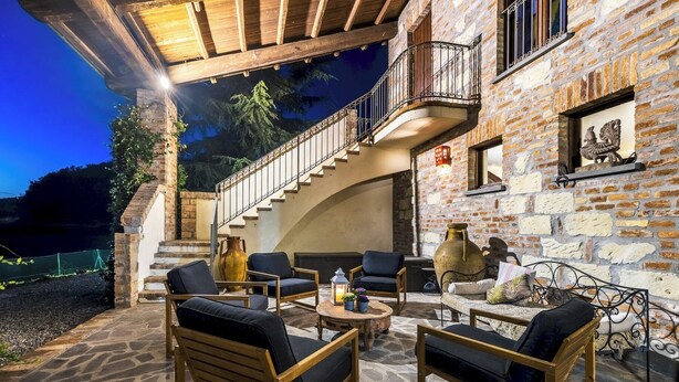 An outdoor patio area with stone flooring, wooden furniture, and a stone wall. - Cascina Monferrato 12, Emma Villas (Sala Monferrato)