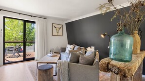 Un salon moderne avec un canapé, une table basse et un grand vase posé sur un piédestal en bois.