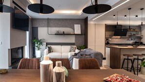 A modern living room with a sofa, dining table, and kitchen area.