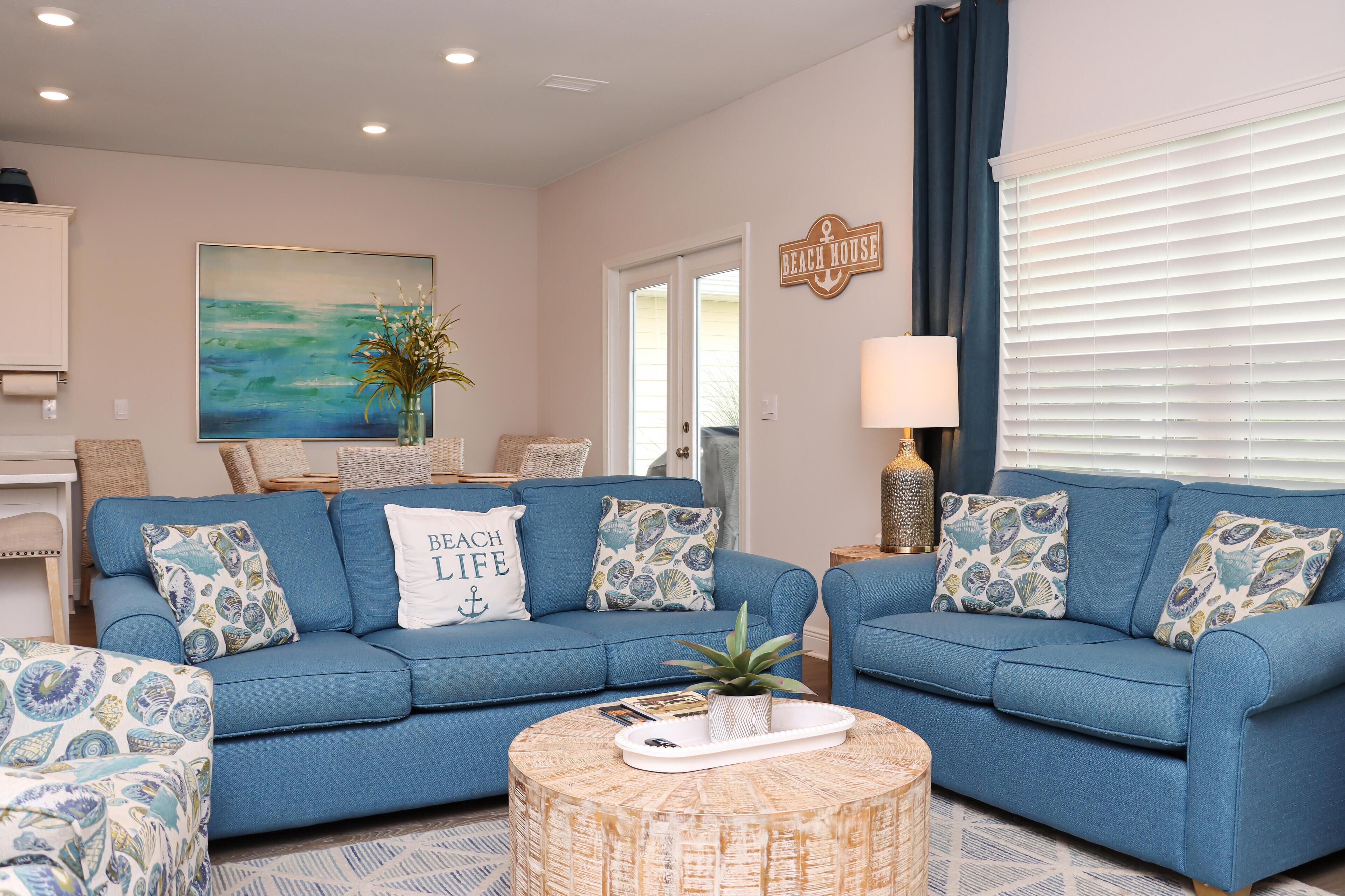 A living room with two blue sofas, a round coffee table, and a painting on the wall.