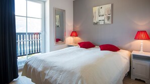 Une chambre à coucher avec un grand lit, deux tables de chevet, une fenêtre donnant sur un beau paysage et un tableau accroché au mur.