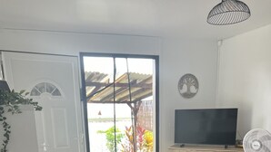 A modern living room with a round table, two stools, a black sofa, a television, and a fan.